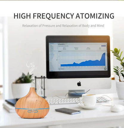 Wood grain essential oil diffuser emitting mist on a desk with a computer, promoting relaxation and stress relief.